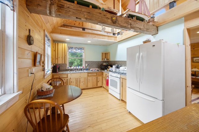 kitchen with wood walls, light hardwood / wood-style floors, tasteful backsplash, white appliances, and light brown cabinetry