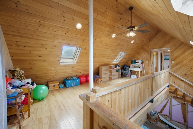 playroom featuring wooden walls, ceiling fan, hardwood / wood-style floors, wooden ceiling, and lofted ceiling with skylight