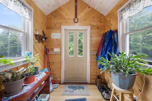 doorway featuring light hardwood / wood-style flooring, wood walls, and vaulted ceiling