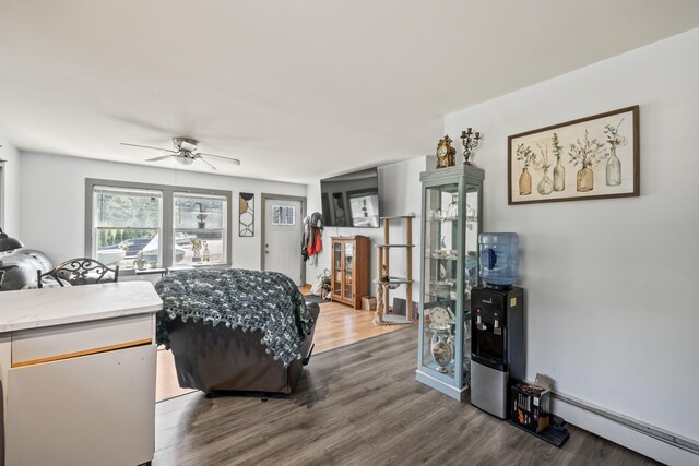 bedroom with ceiling fan, baseboard heating, and wood-type flooring