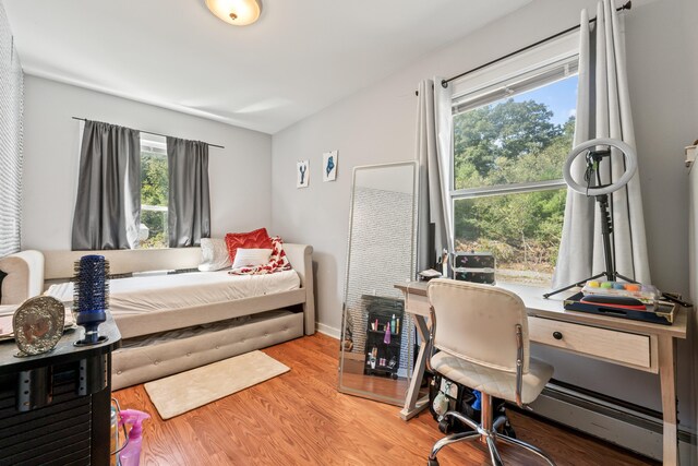 bedroom with a baseboard heating unit and light hardwood / wood-style floors