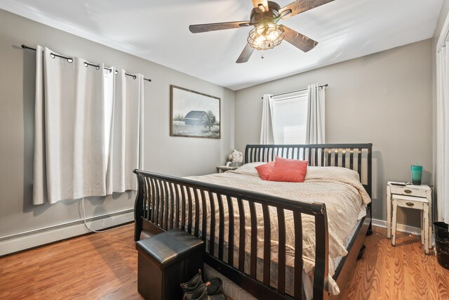 bedroom with ceiling fan, wood-type flooring, and a baseboard radiator