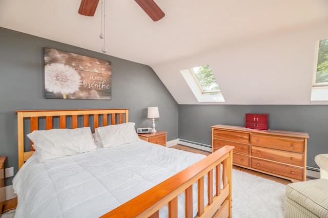 bedroom with lofted ceiling with skylight, baseboard heating, and ceiling fan