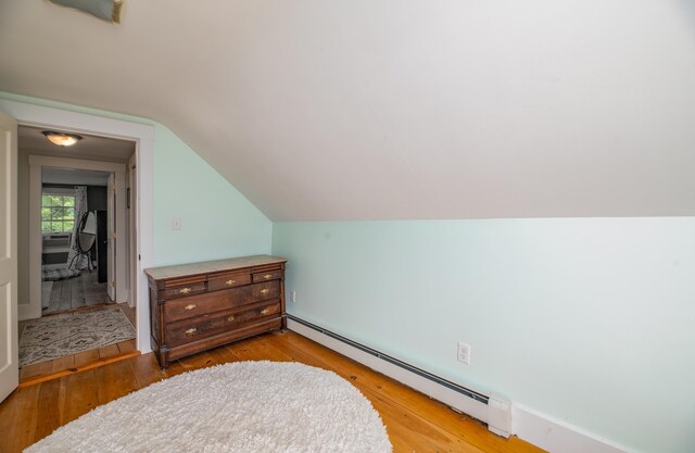 bonus room with lofted ceiling, a baseboard radiator, and light hardwood / wood-style floors