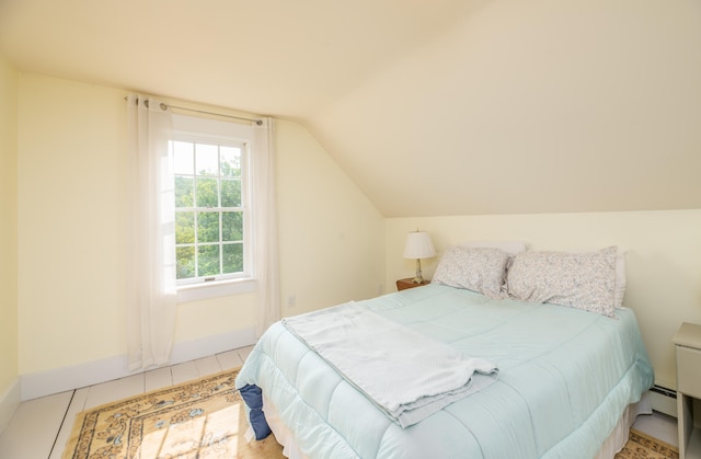 bedroom with a baseboard heating unit, tile patterned floors, and vaulted ceiling