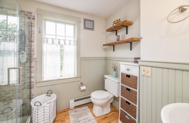 bathroom with a healthy amount of sunlight, wood-type flooring, toilet, and a baseboard heating unit