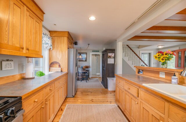 kitchen with range, stainless steel fridge, light hardwood / wood-style flooring, and sink