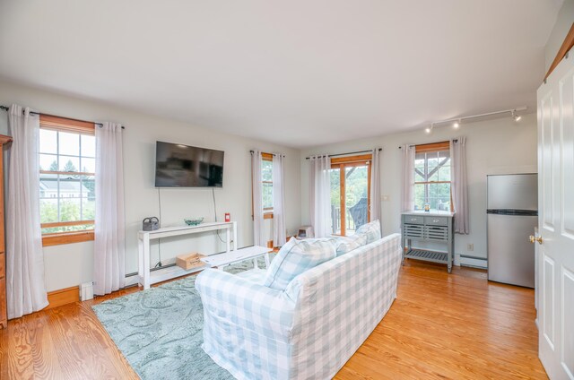 living room with a baseboard radiator, light hardwood / wood-style floors, and plenty of natural light