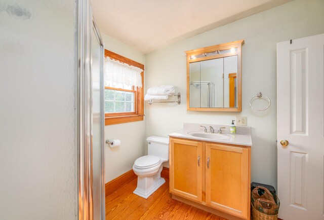 bathroom featuring toilet, an enclosed shower, vanity, and hardwood / wood-style floors