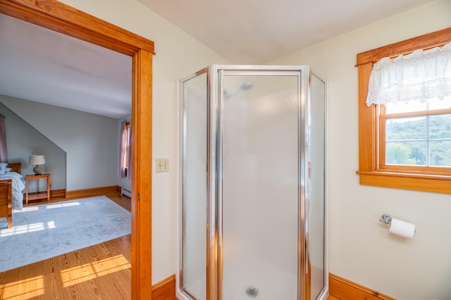 bathroom with an enclosed shower, a baseboard radiator, and wood-type flooring