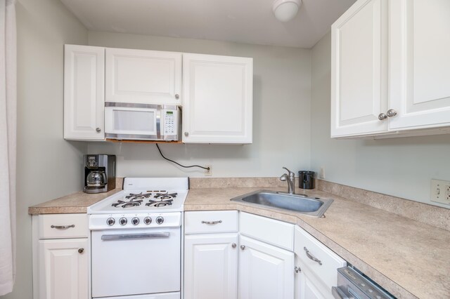 kitchen with white appliances, sink, and white cabinetry