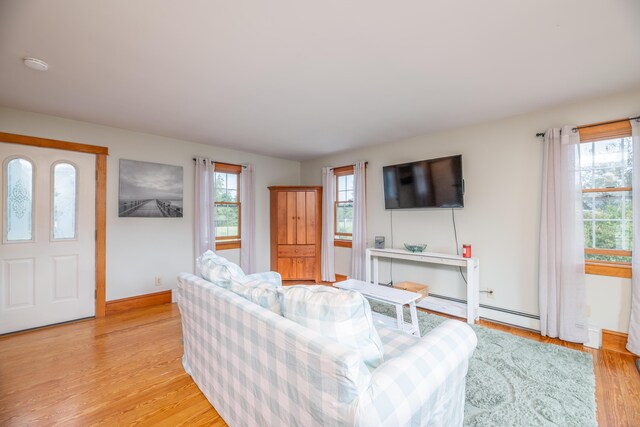 living room with light hardwood / wood-style floors, plenty of natural light, and a baseboard heating unit