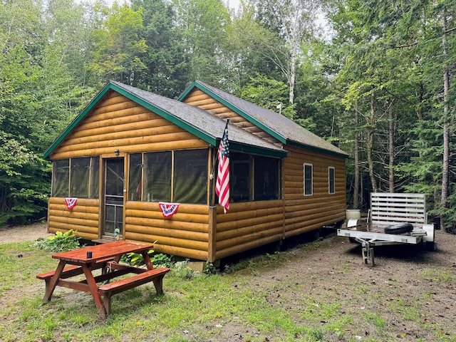 view of home's exterior featuring log veneer siding and a sunroom