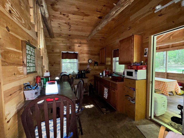 kitchen with wood walls, wooden ceiling, and lofted ceiling with beams