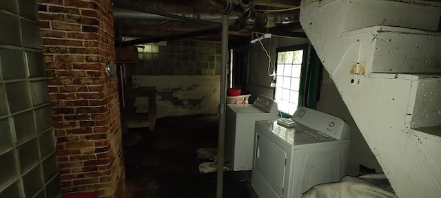 washroom with washing machine and clothes dryer and brick wall