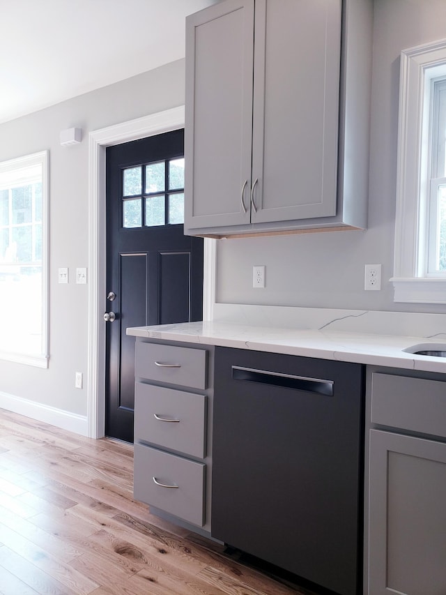 kitchen featuring gray cabinets, light stone countertops, and a healthy amount of sunlight