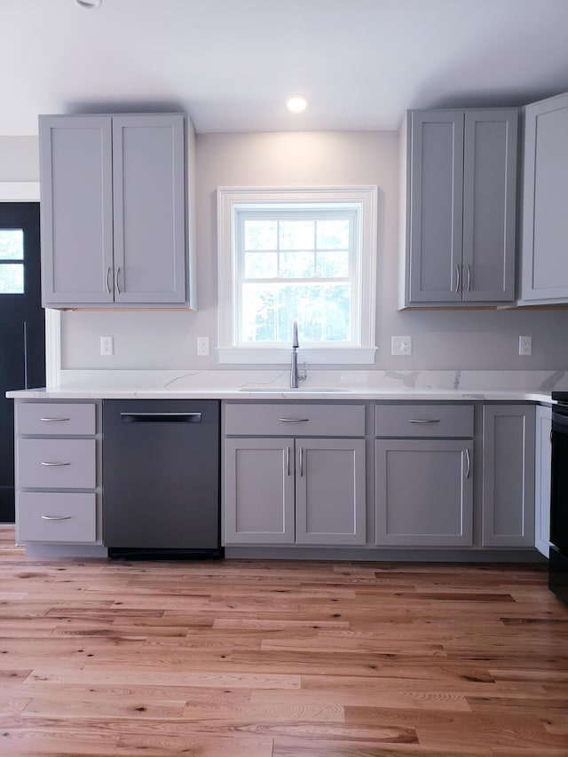 kitchen with dishwasher, sink, light wood-type flooring, light stone countertops, and gray cabinets