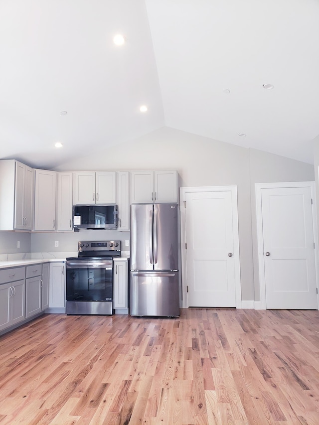 kitchen with vaulted ceiling, light hardwood / wood-style floors, and stainless steel appliances