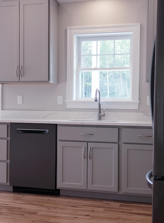 kitchen with light hardwood / wood-style floors, stainless steel appliances, gray cabinets, and light stone counters