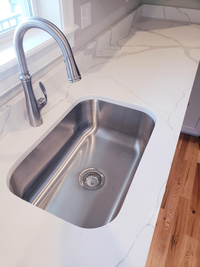 interior details featuring sink, light stone counters, and light wood-type flooring