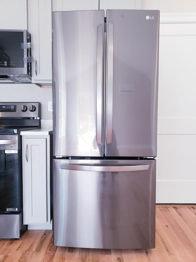 kitchen featuring appliances with stainless steel finishes, light hardwood / wood-style flooring, and white cabinetry