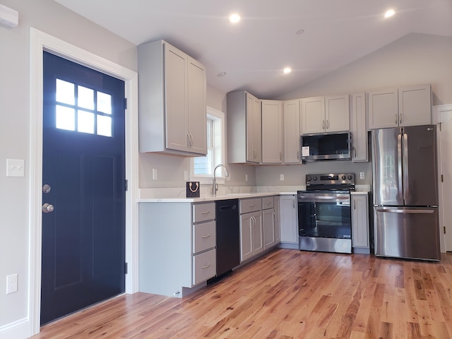 kitchen featuring gray cabinetry, vaulted ceiling, light hardwood / wood-style floors, and stainless steel appliances