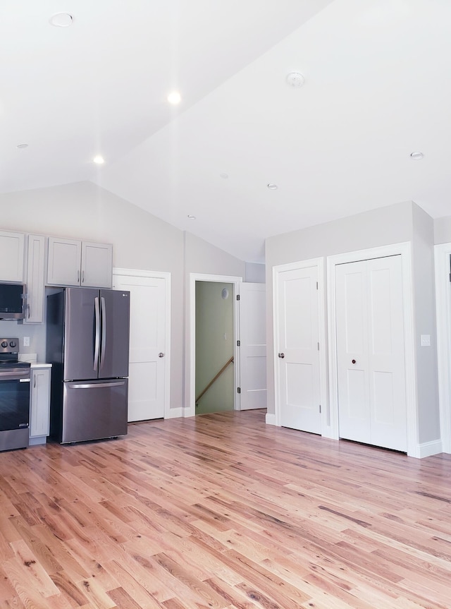 kitchen with light hardwood / wood-style floors, stainless steel appliances, and lofted ceiling