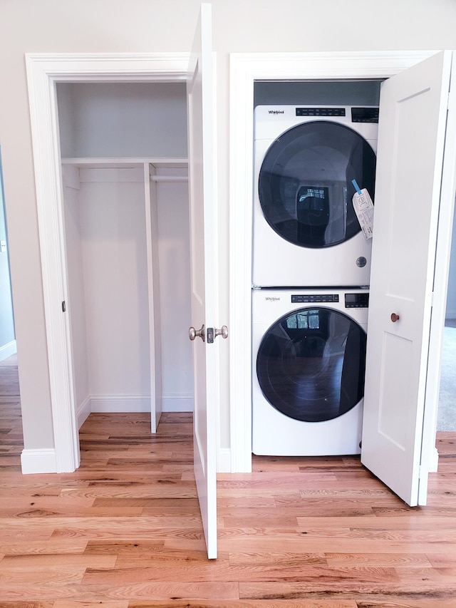 washroom featuring stacked washer / dryer and light hardwood / wood-style flooring