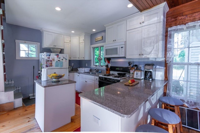 292300 Main Rd, Islesboro, ME 04848 - kitchen featuring a sink, a peninsula, white appliances, white cabinets, and dark stone counters