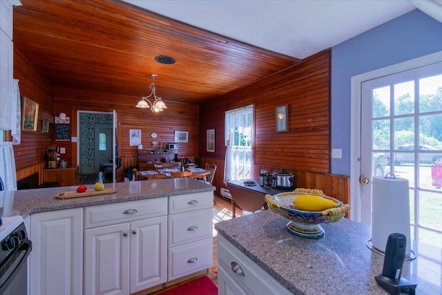 292300 Main Rd, Islesboro, ME 04848 - kitchen with white cabinets, wood walls, a peninsula, black range with gas cooktop, and a notable chandelier