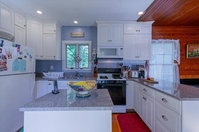 292300 Main Rd, Islesboro, ME 04848 - kitchen featuring a peninsula, white cabinets, wooden walls, and white appliances