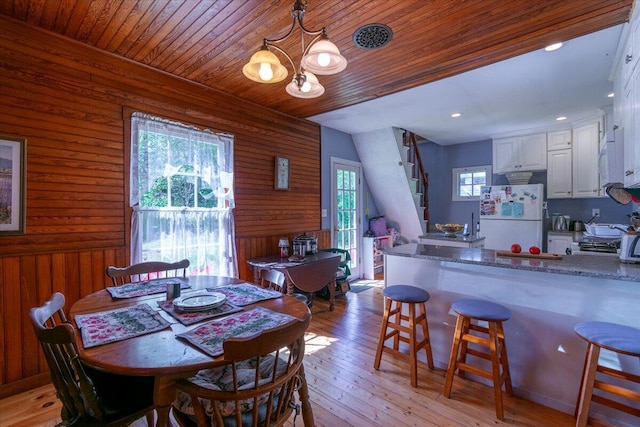 292300 Main Rd, Islesboro, ME 04848 - dining space featuring light wood-style flooring, wooden walls, stairway, an inviting chandelier, and wooden ceiling