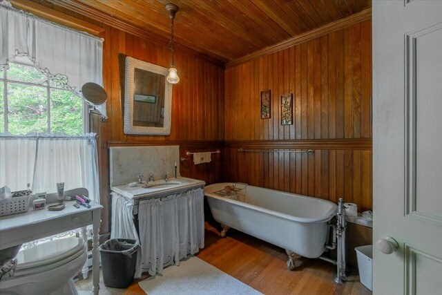 bathroom with hardwood / wood-style floors, wood walls, a bathing tub, wood ceiling, and toilet