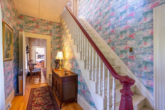 stairway featuring a baseboard heating unit and wood-type flooring