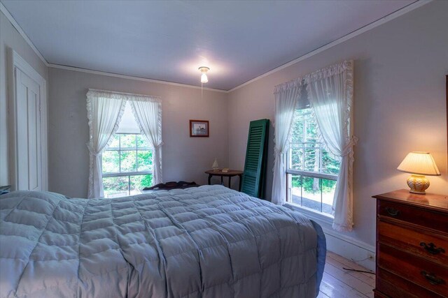 bedroom with hardwood / wood-style floors, multiple windows, and crown molding