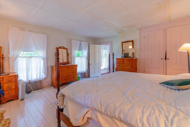 bedroom with light hardwood / wood-style floors and a paneled ceiling