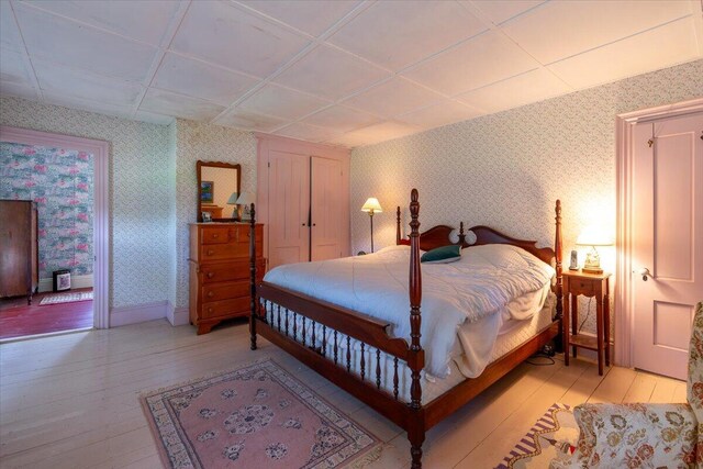 bedroom with light hardwood / wood-style floors and a drop ceiling