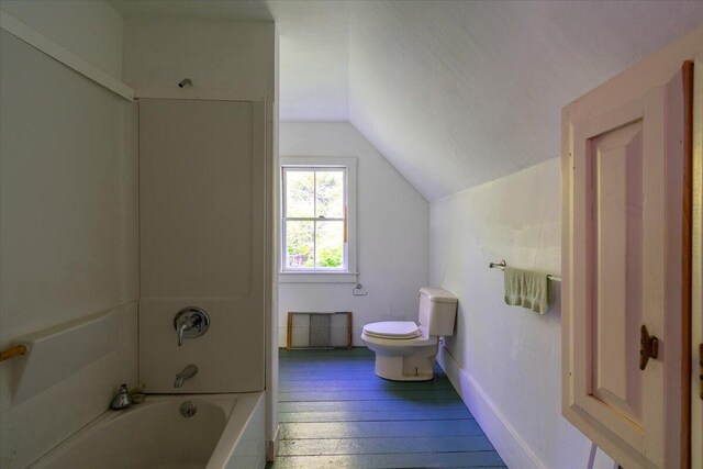 bathroom featuring hardwood / wood-style flooring, shower / washtub combination, lofted ceiling, and toilet