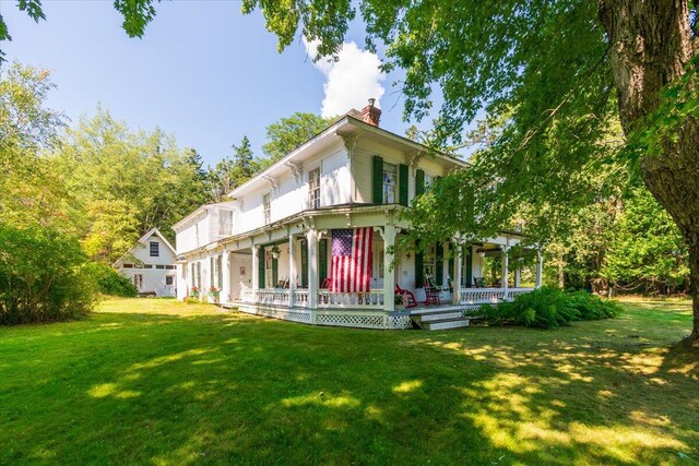 rear view of house featuring a lawn and covered porch