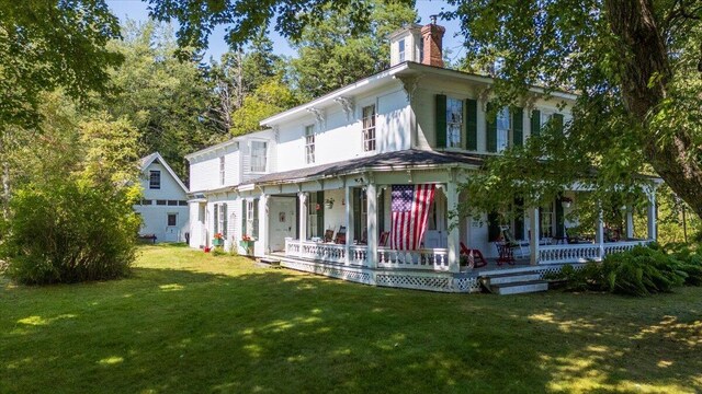 rear view of house with a lawn and a porch