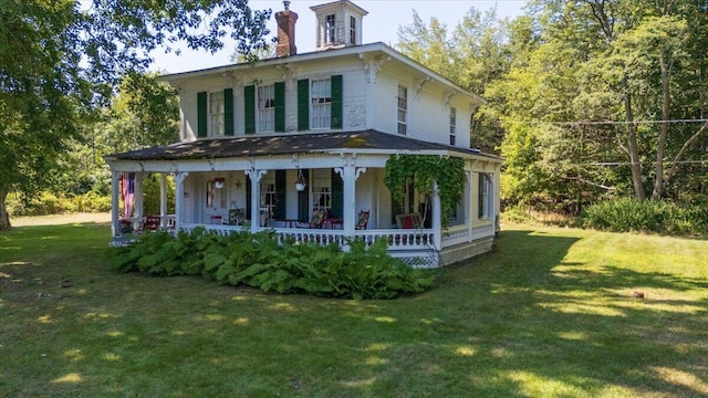 back of property with a yard and covered porch