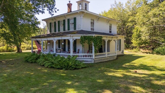 rear view of property featuring a lawn and a porch