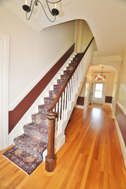 staircase featuring an inviting chandelier and wood-type flooring