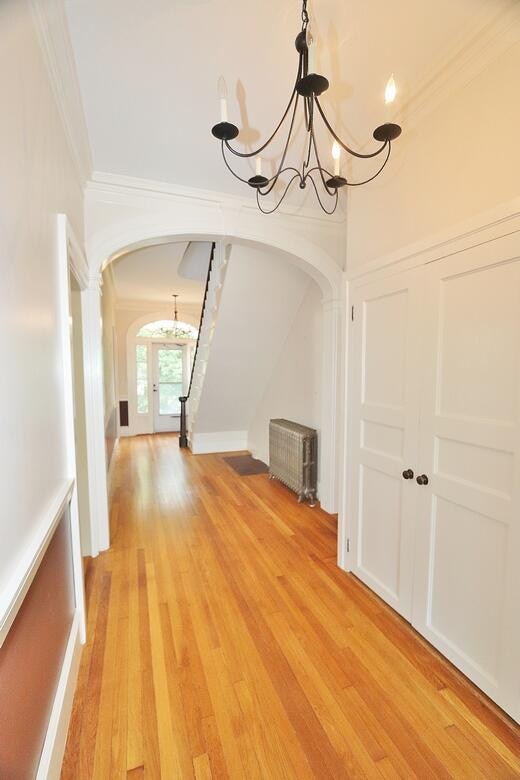 interior space with ornamental molding, an inviting chandelier, and hardwood / wood-style flooring