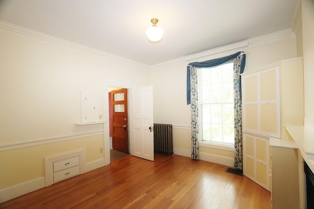 interior space with radiator, wood-type flooring, and crown molding