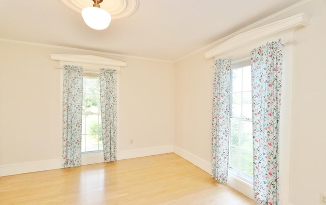 empty room with light hardwood / wood-style floors, a healthy amount of sunlight, and crown molding