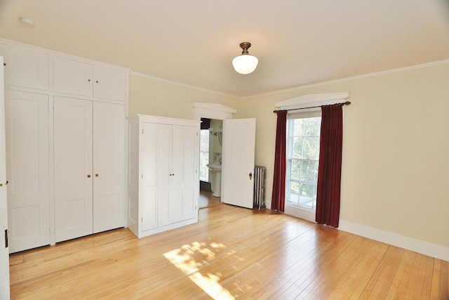 unfurnished bedroom with radiator heating unit, light wood-type flooring, connected bathroom, and crown molding