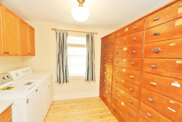 laundry area with washer and clothes dryer, cabinets, and light hardwood / wood-style flooring