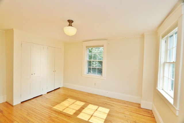 unfurnished bedroom with light wood-type flooring and a closet