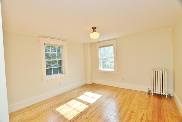 unfurnished room with light wood-type flooring, crown molding, radiator, and plenty of natural light